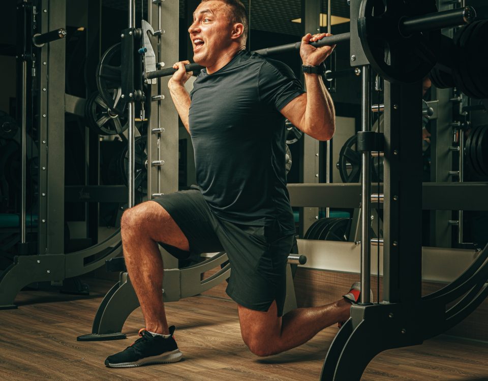 Fit man doing squats in a training machine