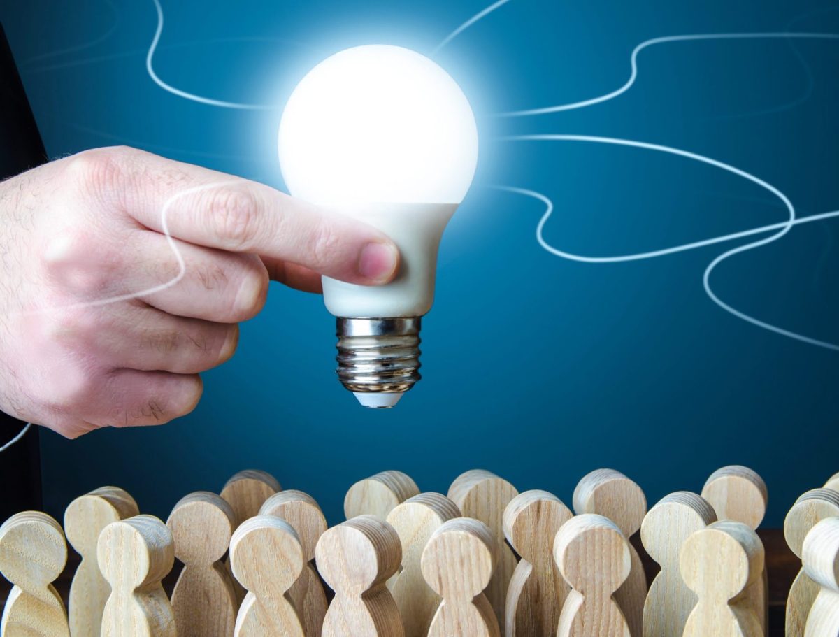A man holds an idea light bulb above the crowd. Project leader. Teamwork. Brainstorming. Creativity. Informant. Statistics, survey. Research and development. Enlightenment and education