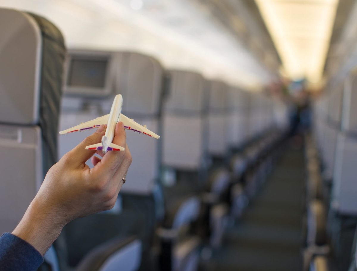 Close-up of a hand holding a model airplane inside a large aircraft