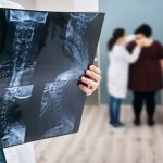 Doctor holds an x-ray of a cervical spine over background osteopath check-up overweight woman's