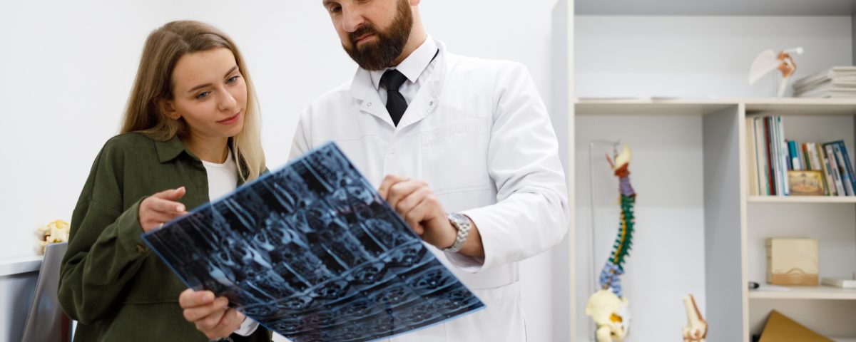 Doctor orthopedist or traumatologist shows tomographic picture to his patient