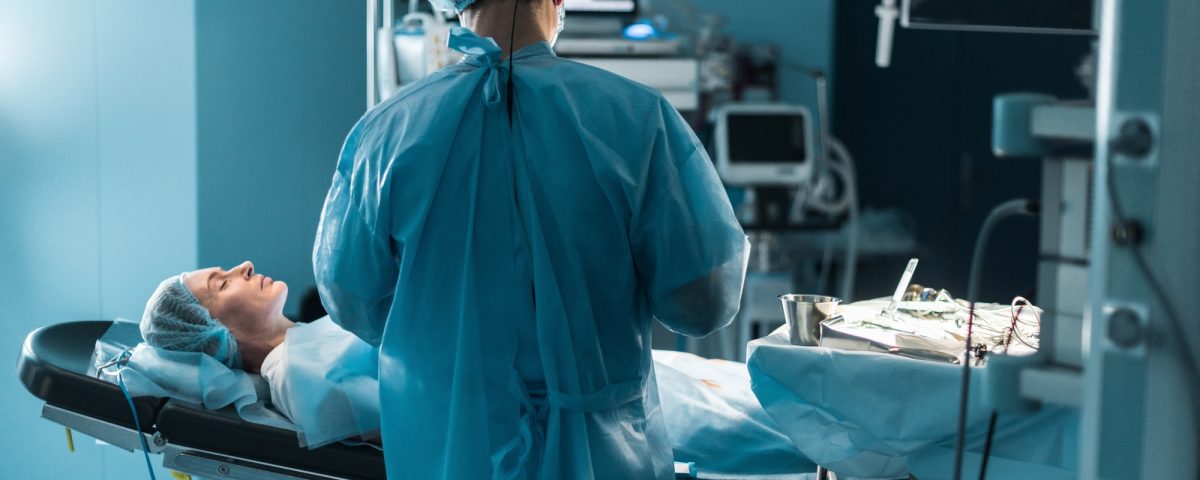 back view of surgeon operating patient in operating room